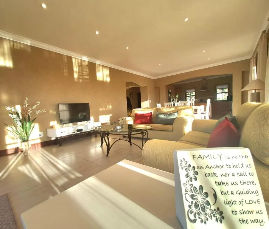 Bright open-plan lounge with comfortable seating, TV, and natural light