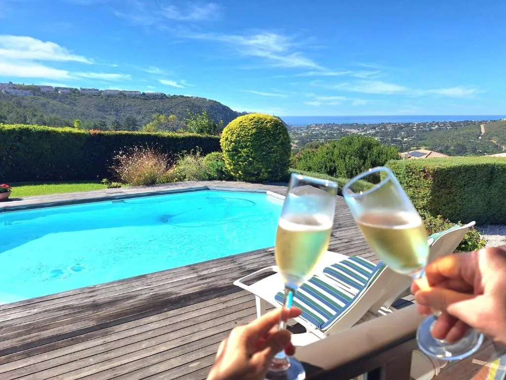 Sparkling swimming pool with ocean view and champagne celebration on wooden deck