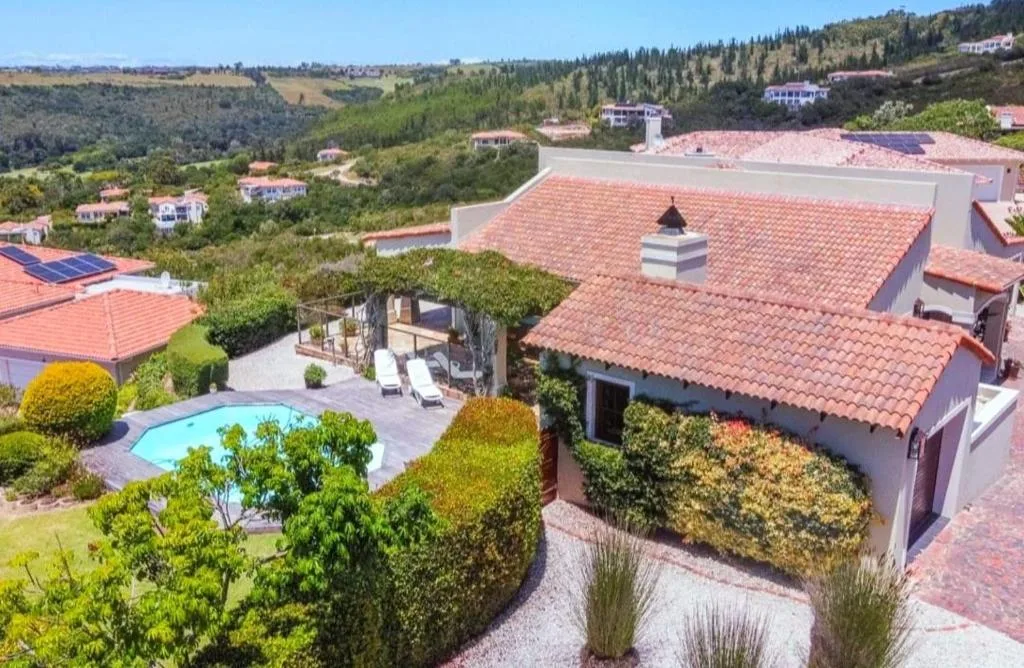 Aerial view of property with pool, terracotta roofs, and forested hillside landscape