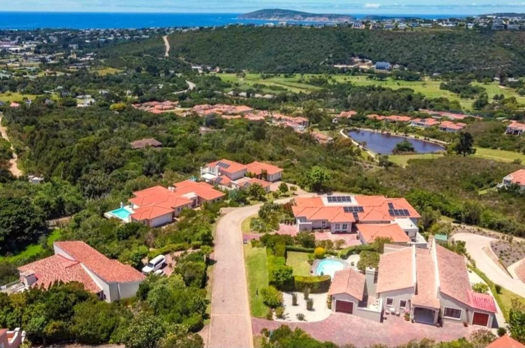 Aerial view of Plettenberg Bay suburb with ocean, mountains, and scattered homes