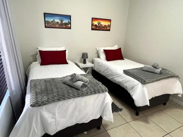 Twin bedroom with white linens, burgundy pillows, and framed artwork