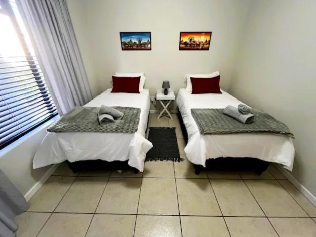 Twin bedroom with two single beds, burgundy pillows, and tiled flooring