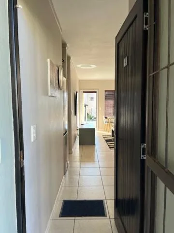 Narrow hallway with tiled flooring and black doors leading through property