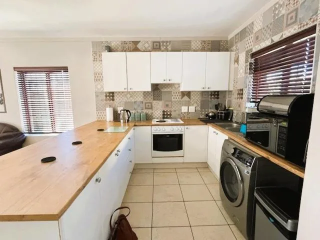 Modern white kitchen with wooden countertops and patterned backtile