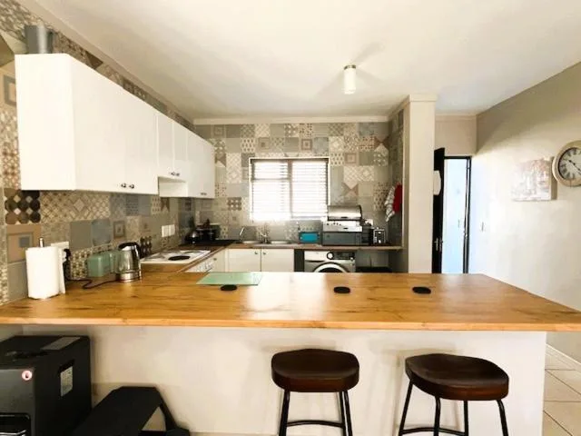 Modern kitchen with white cabinetry, wooden countertop, and bar seating