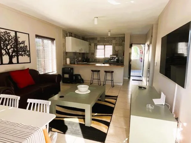 Open-plan living area with sofa, TV, and modern kitchen in background