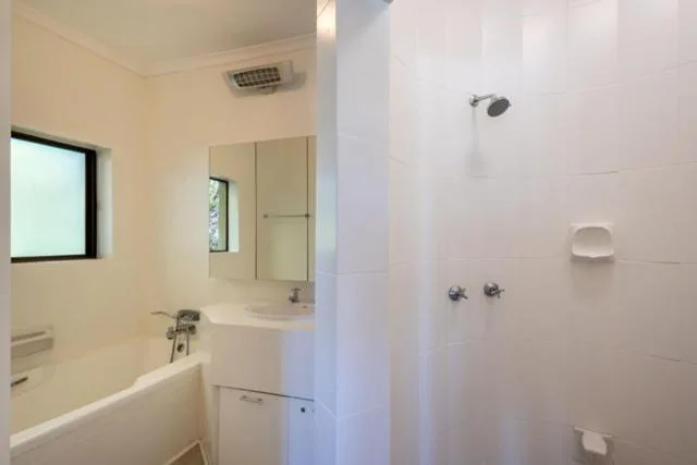 Modern bathroom with white tiles, vanity sink, bathtub, and shower enclosure