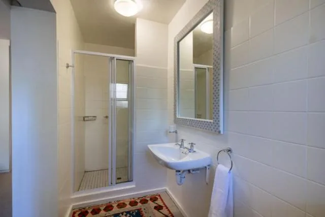 Modern bathroom with shower stall, vanity sink, and large mirror