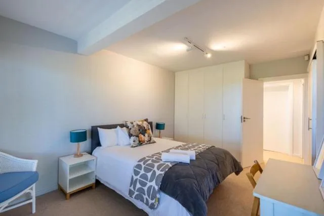 Bright modern bedroom with white built-in wardrobes and single bed