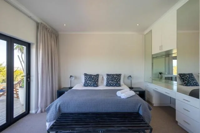 Modern bedroom with blue bedding, white dresser, and patio door access