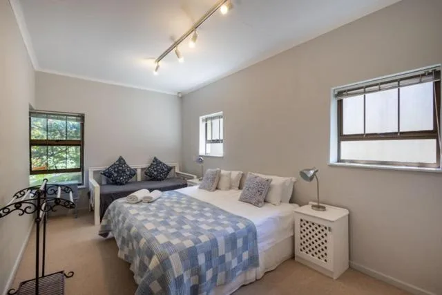 Bright bedroom with queen bed, patterned bedding, and garden views through windows