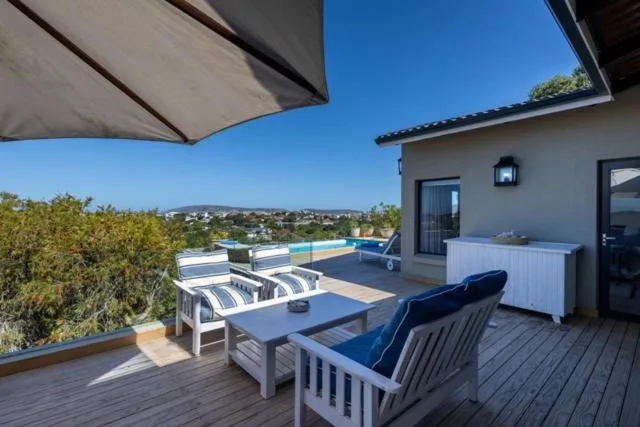 Expansive deck with seating, loungers, umbrellas overlooking town