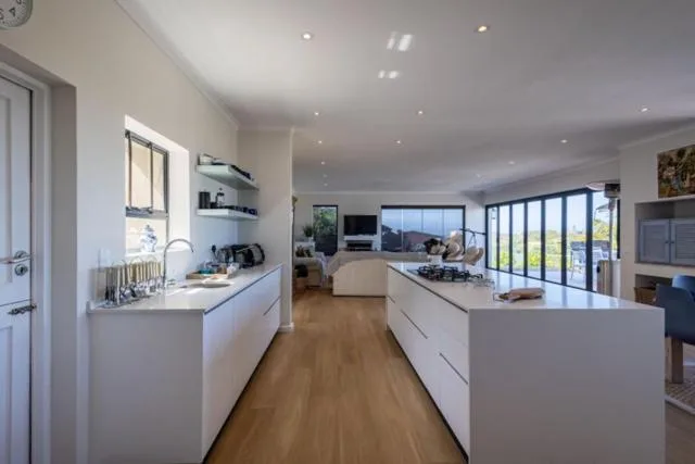Modern open-plan kitchen with white cabinetry and island bench overlooking lounge area