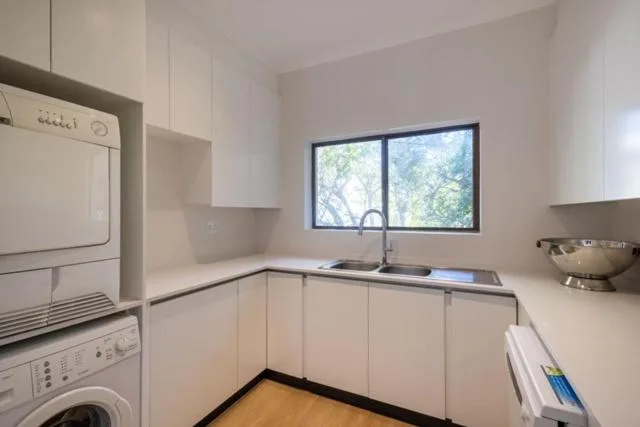 Modern kitchen with white cabinetry, sink, and garden view window