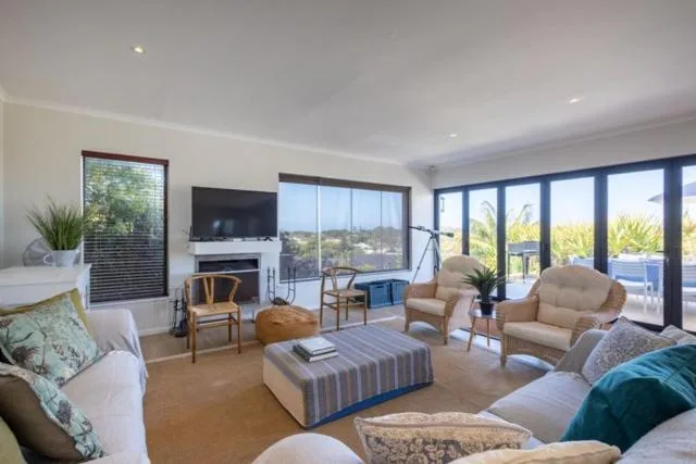 Spacious living room with cream furnishings, fireplace, and ocean views through glass doors