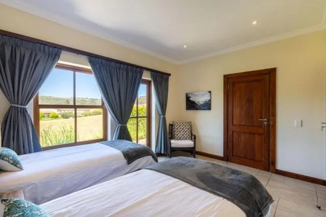 Bright bedroom with twin beds overlooking garden landscape through large windows