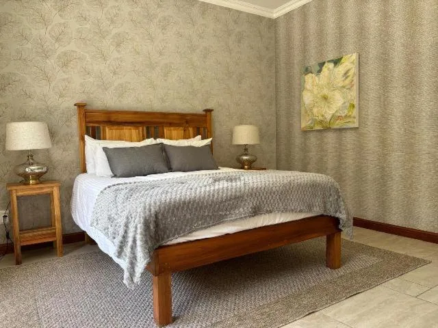 Wooden bed with white bedding and gray throw in spacious bedroom