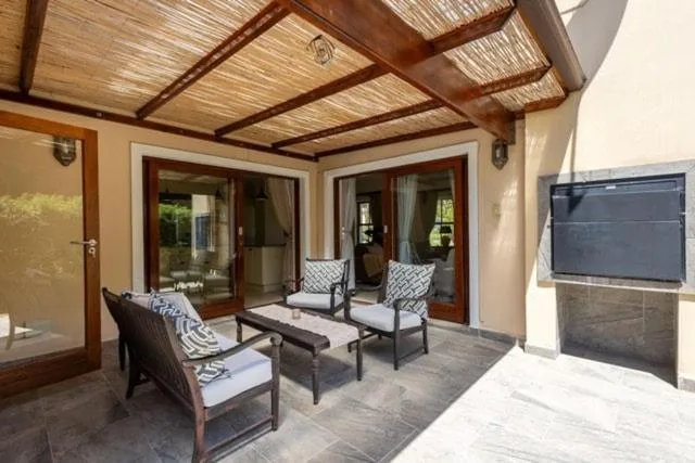 Covered patio with wooden beams, comfortable seating, and glass doors