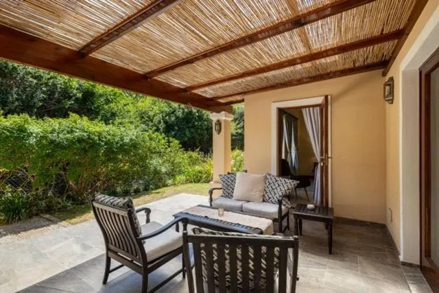 Covered patio with comfortable seating overlooking lush green garden