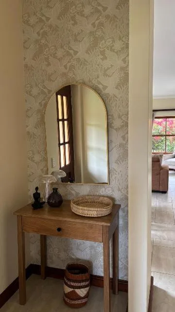 Wooden vanity with arched mirror and decorative accessories in entryway