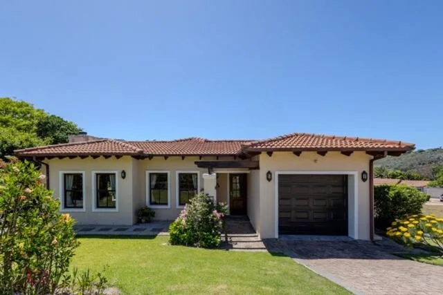 Modern beige house with terracotta roof and garage in manicured garden