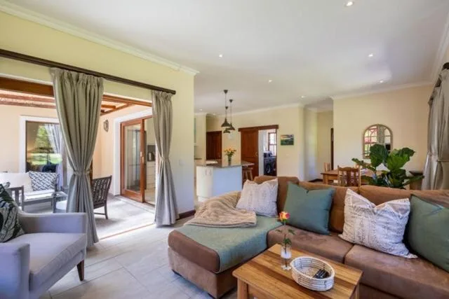 Spacious lounge with brown sofa, decorative pillows, and access to outdoor deck