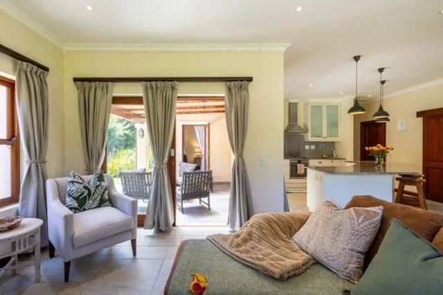 Spacious lounge with sofa, armchair, and open-plan kitchen view