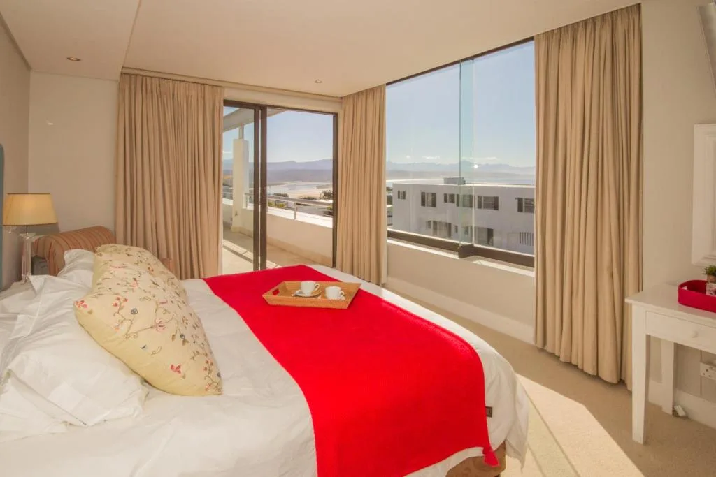 Bright bedroom with ocean views through sliding glass doors and curtains