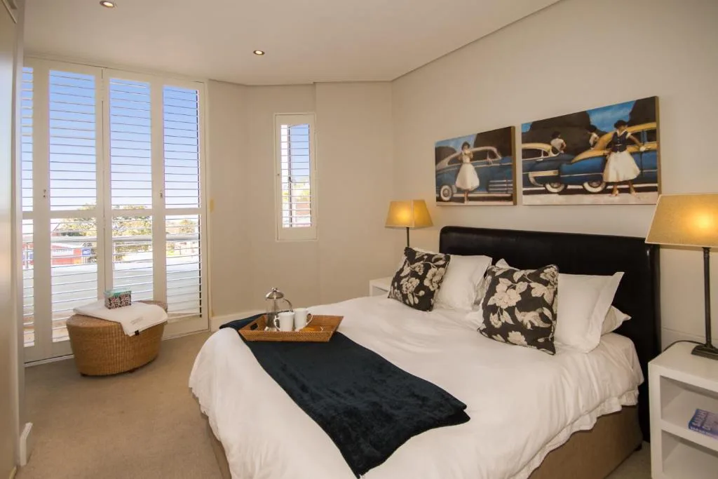 Spacious bedroom with queen bed, black headboard, and large windows overlooking town