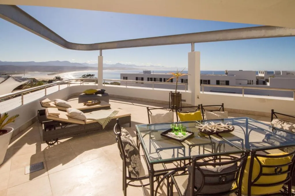 Spacious upper deck with lounge chairs, dining table, and lagoon views