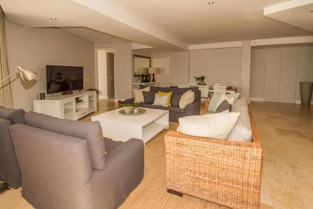 Spacious open-plan lounge with multiple seating areas and television setup