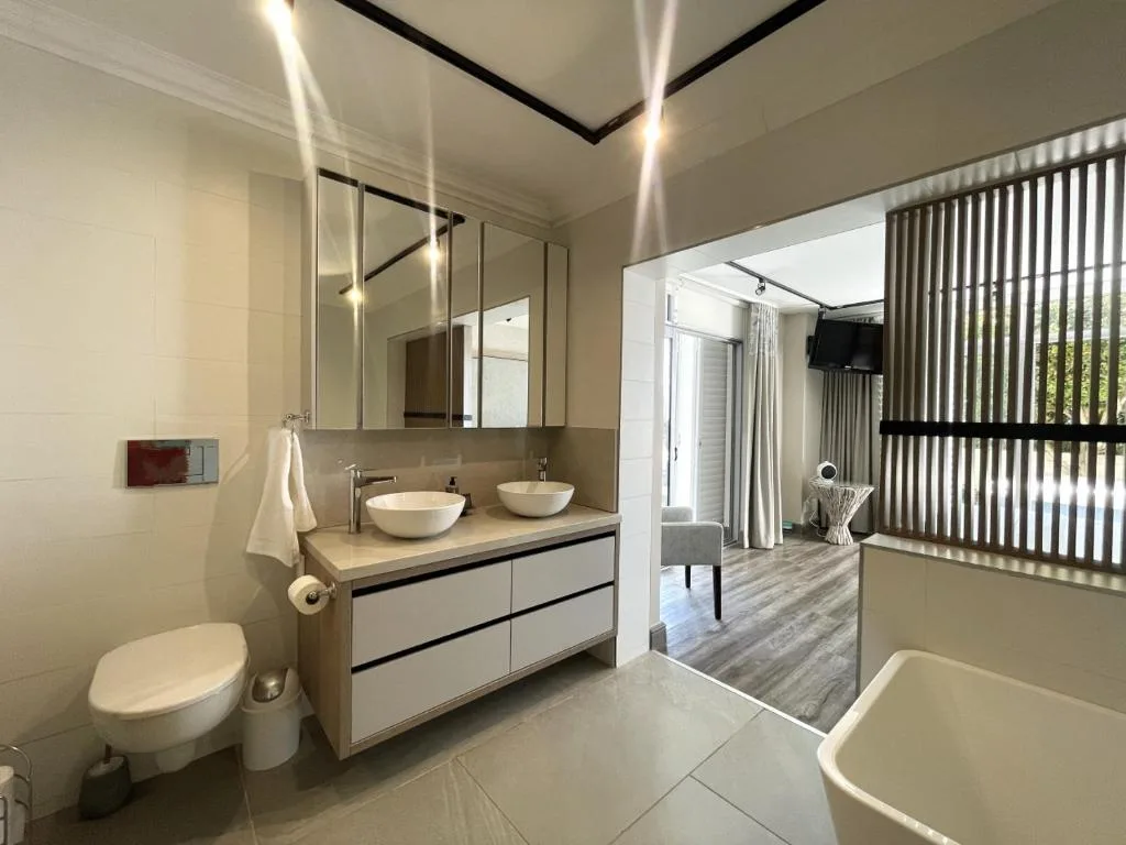 Modern bathroom with dual vessel sinks, toilet, and freestanding bathtub