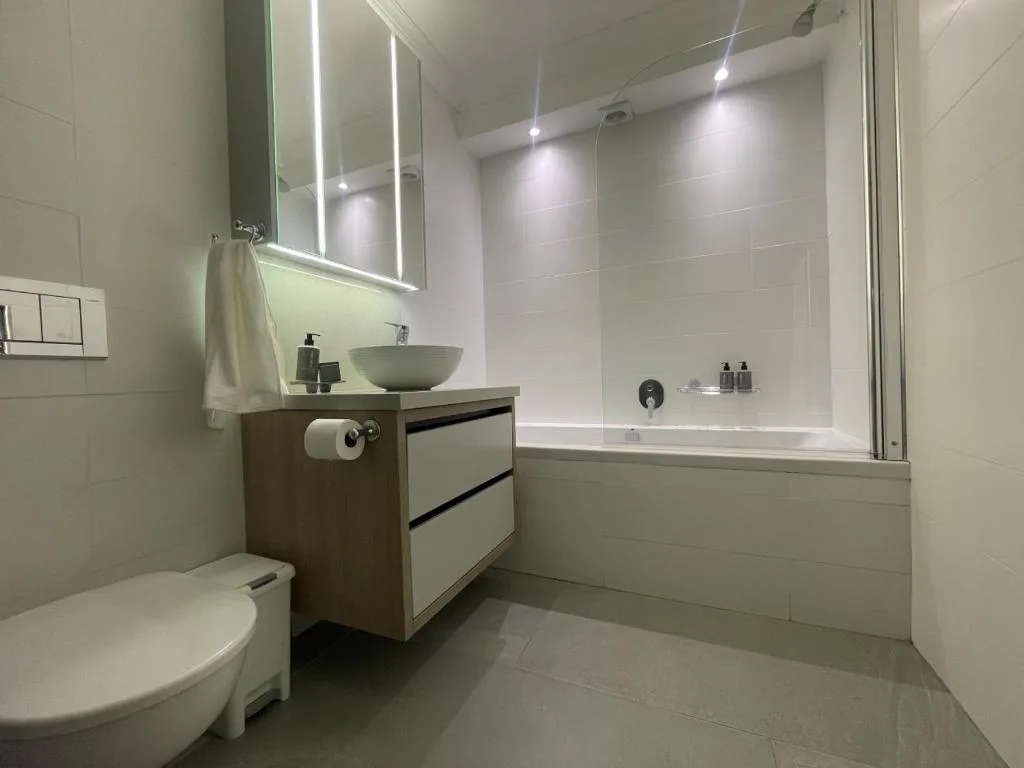 Modern bathroom with vanity sink, mirror, toilet, and shower enclosure