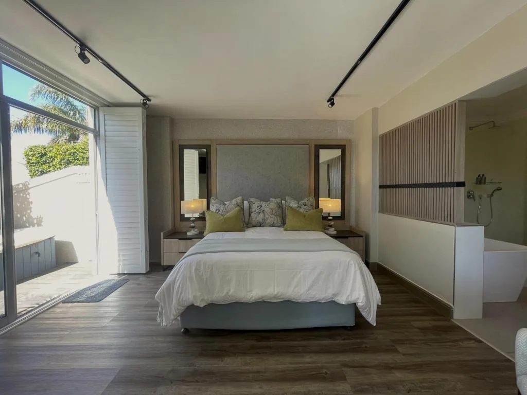 Modern bedroom with queen bed, ensuite bathroom, and garden access door