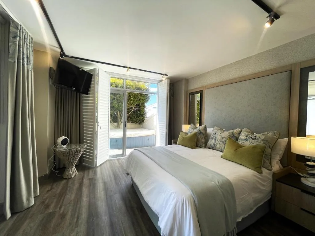 Modern bedroom with queen bed, green cushions, and sliding doors to outdoor patio