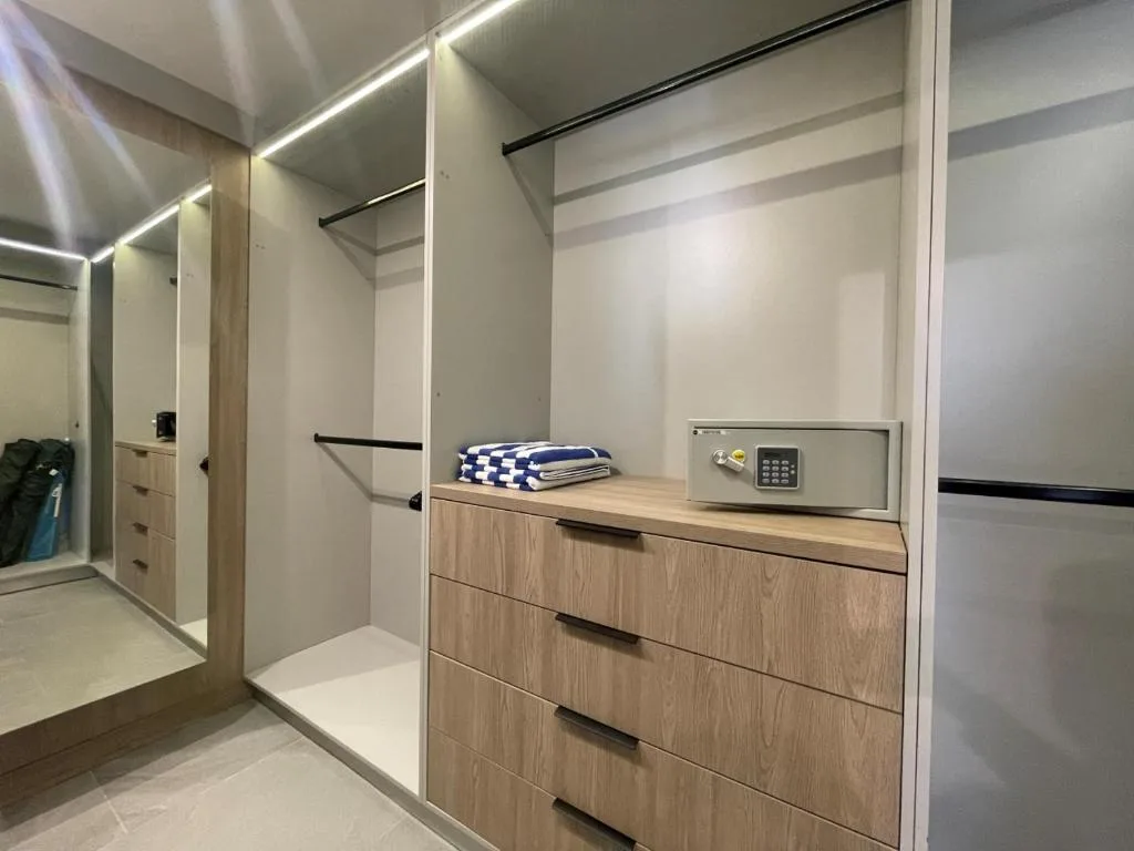 Modern bedroom with built-in wardrobes, wooden drawers, and safe storage
