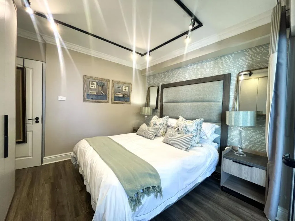 Modern bedroom with black canopy bed, neutral bedding, and contemporary decor