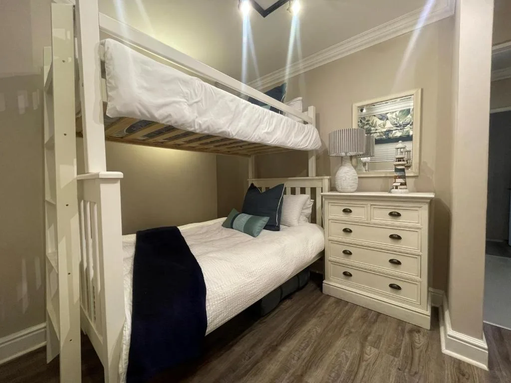 Bright bedroom with bunk bed, cream furniture, and modern lighting fixtures