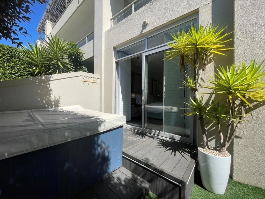 Modern patio with hot tub, tropical plants, and glass sliding doors