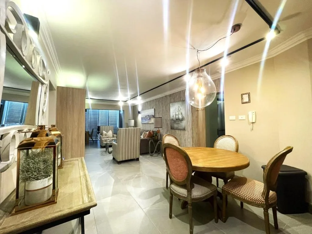 Modern dining area with wooden table and upholstered chairs, open-plan layout