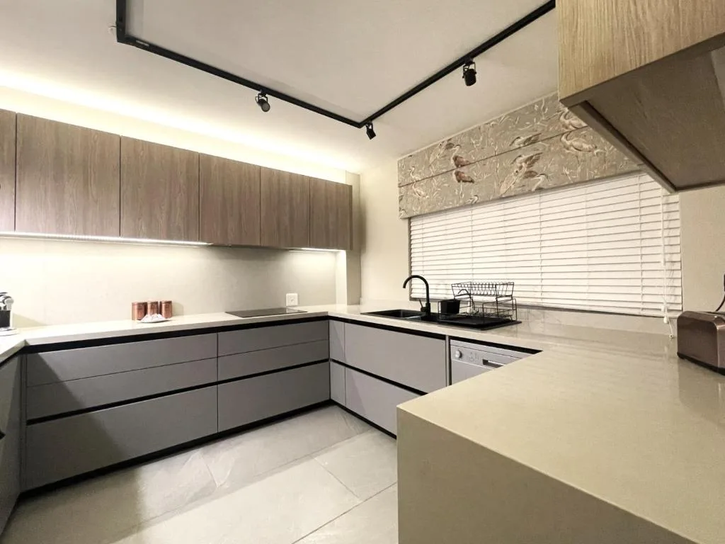 Modern kitchen with grey cabinetry, white countertops, and stainless steel sink