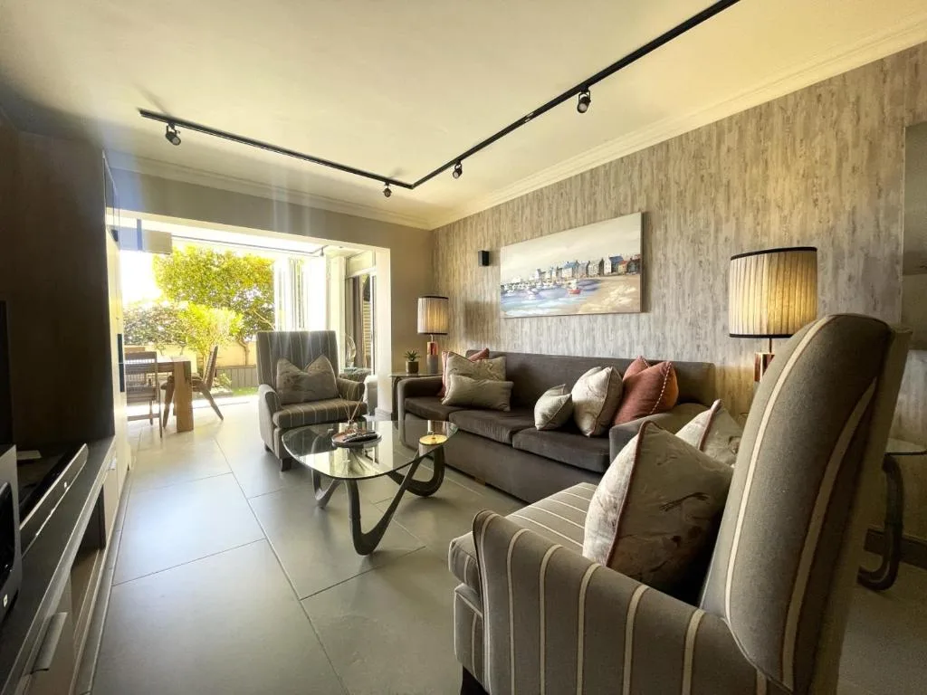 Modern lounge with gray sofa, armchairs, and glass doors opening to outdoor deck