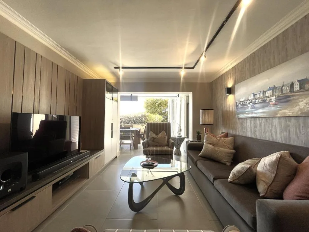 Modern lounge with sofa, TV, and open deck view beyond