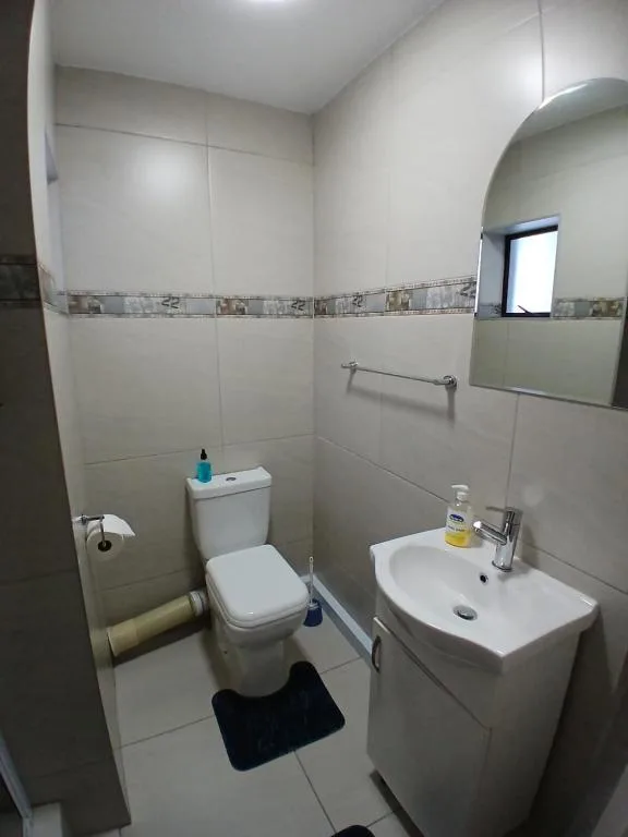 Clean bathroom with white toilet, sink vanity, and tiled walls