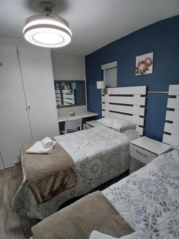 Bright bedroom with two beds and blue accent wall