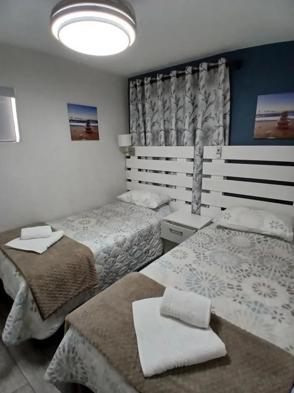 Twin bedroom with white slatted headboards and patterned curtains