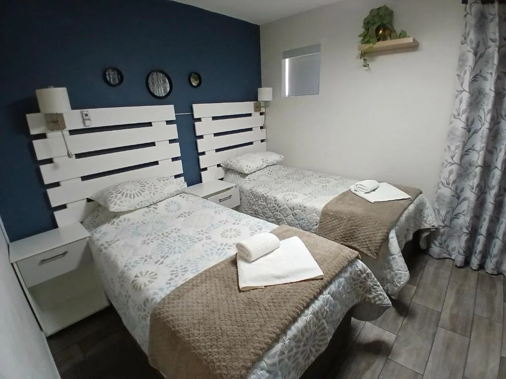 Twin bedroom with white slatted headboards and neutral bedding, navy feature wall