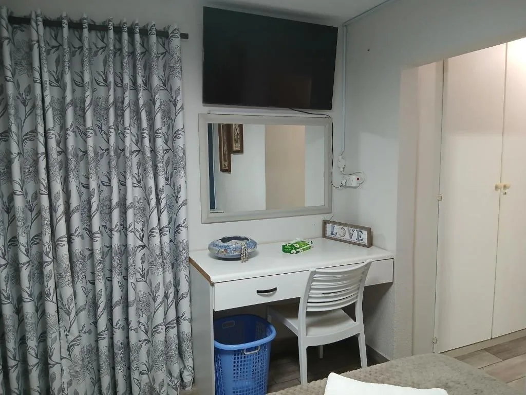 Bedroom with vanity desk, mirror, TV, and patterned curtains