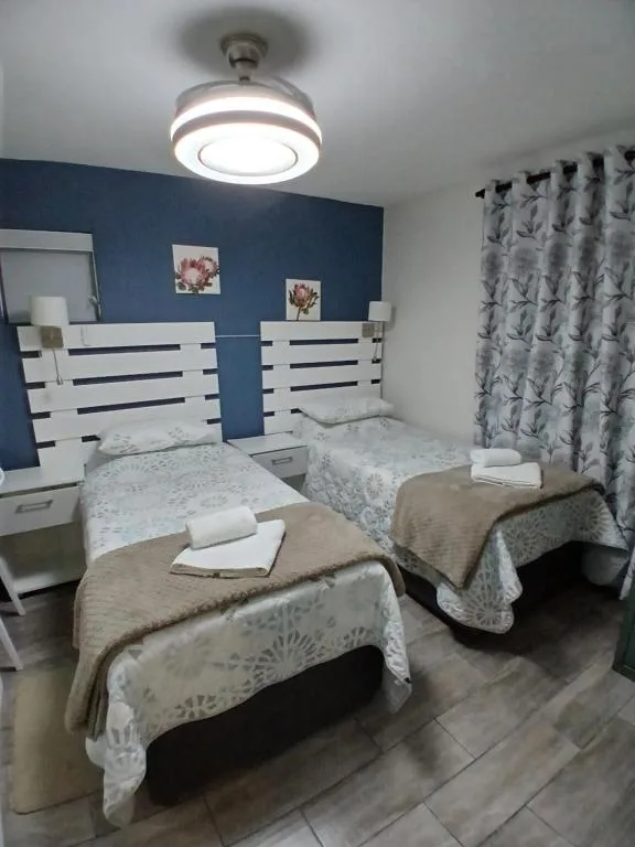 Twin bedroom with white headboards, blue accent wall, and modern ceiling fan