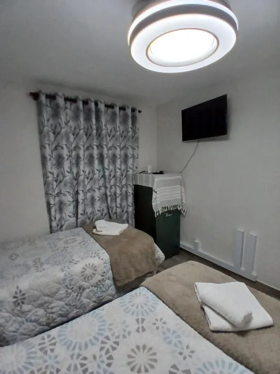 Neat bedroom with twin beds, patterned curtains, and wall-mounted TV